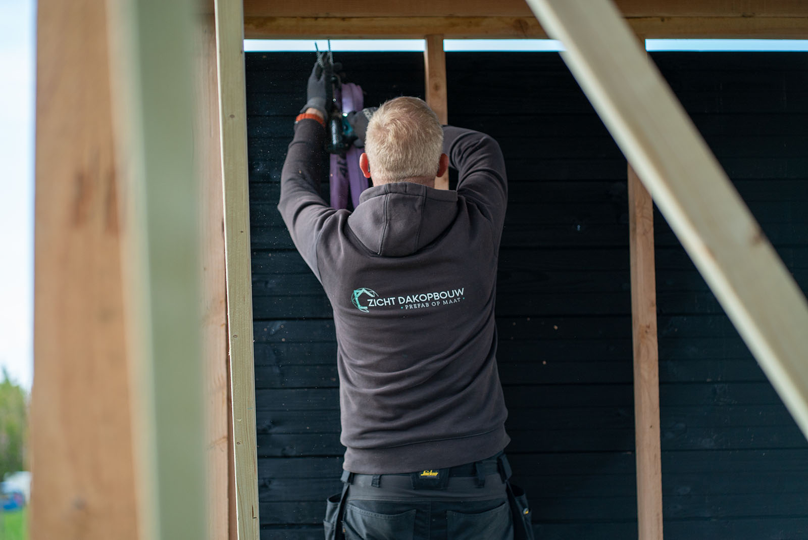 Monteur van Zicht Dakopbouw werkt aan een houten prefab element